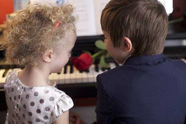A boy and girl, in their Sunday best, sitting side by side on a piano bench, with a single rose on the keys (this photo was a present for the inmate